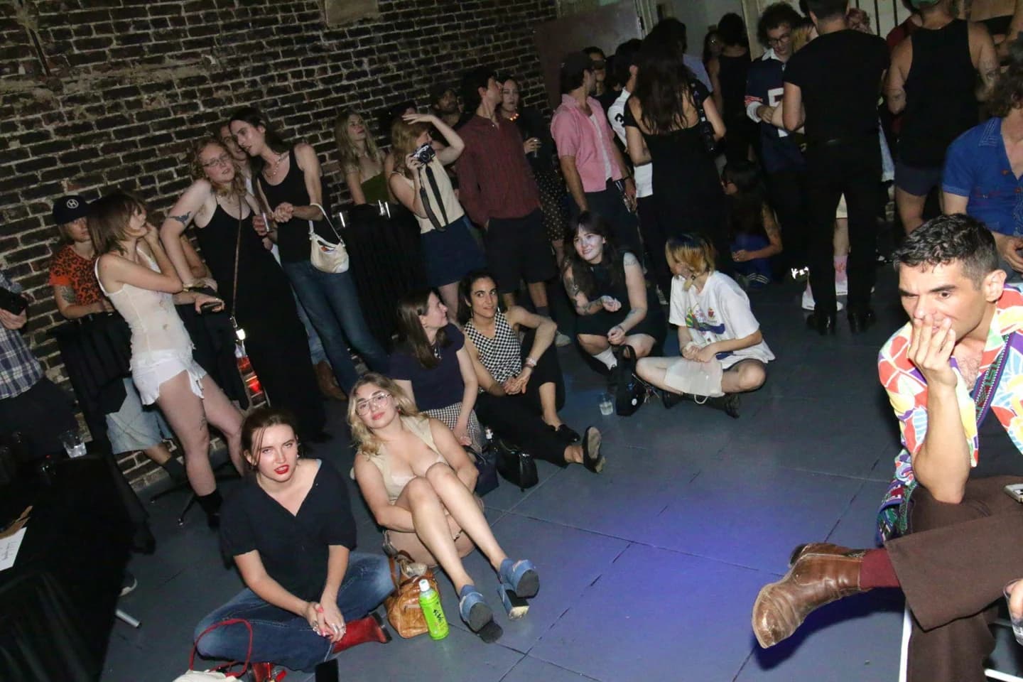 A crowd gathered beside a brick wall
