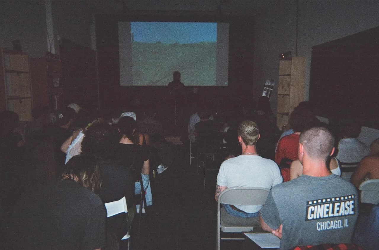 A seated audience watching a presentation beneath a projection screen